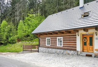 Roubenka Beneška od příjezdové cesty, roubená stěna a šindelová střecha na okraji lesa